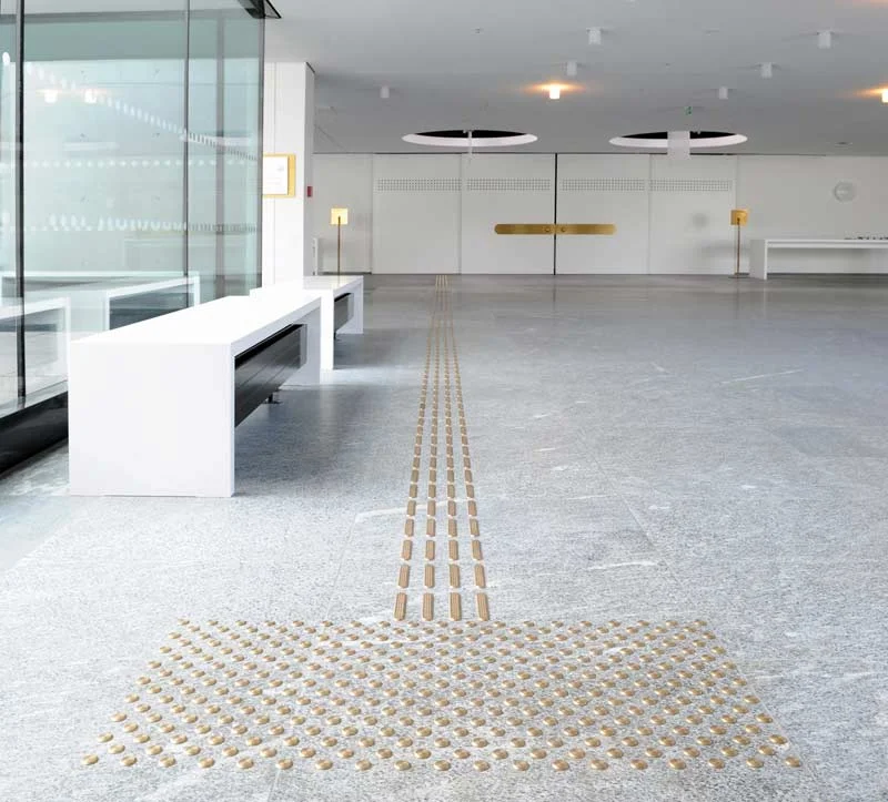 Abbildung des taktilen Leitsystems  in der Eingangshalle mit Rippen ud Noppen aus Messing. 
